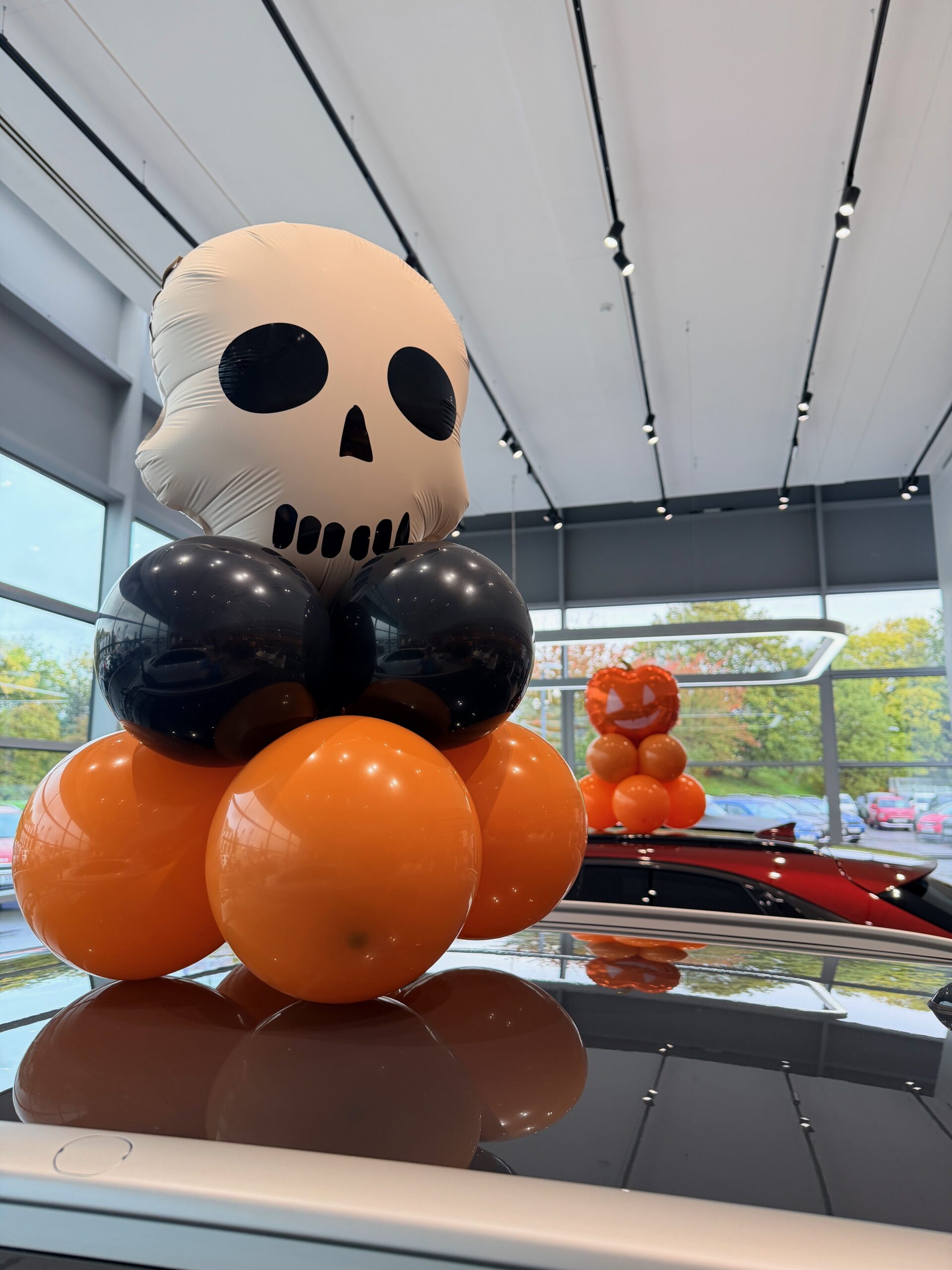 Halloween balloon décor on a car in a dealership showroom